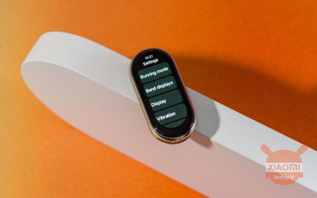 xiaomi mi band 8 su sfondo arancione poggiata su un piedistallo bianco