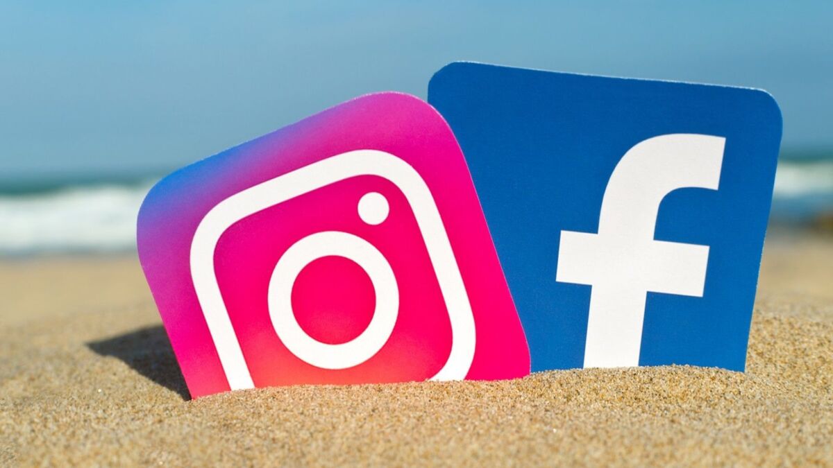 Facebook- och Instagram-ikoner på stranden och med havet i bakgrunden