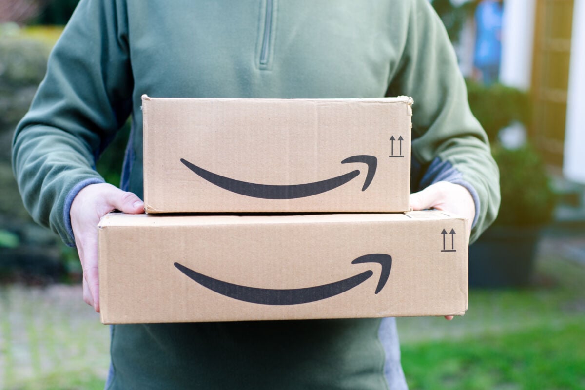 Mann hält Amazon-Päckchen aus Pappe in seinen Händen