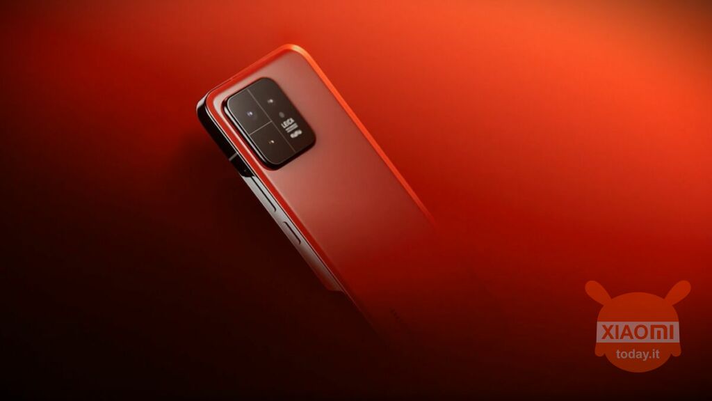 Parte posteriore dello smartphone Xiaomi 14 in una tonalità di rosso lucido. Il telefono presenta un modulo fotocamera rettangolare con tre lenti. Lo sfondo è un degradato di rosso che sfuma dal più scuro al più luminoso