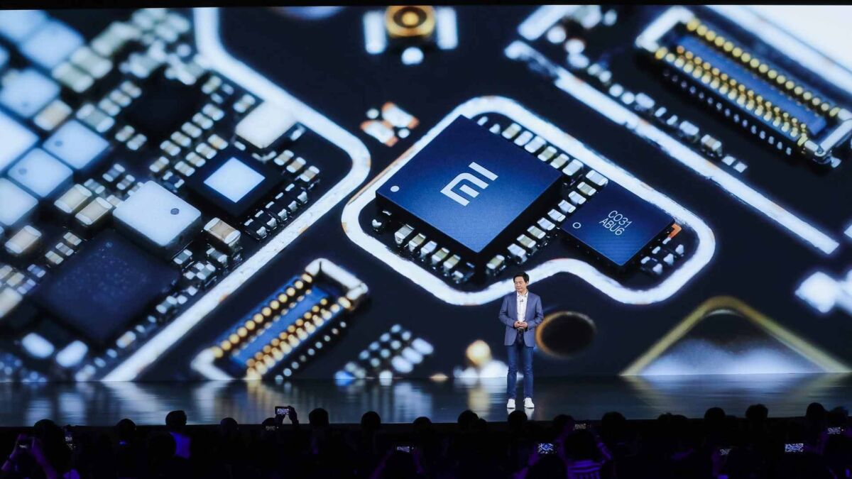 Lei Jun, CEO of Xiaomi, presents the new proprietary chipset with 'Mi' logo. Detail of the circuit highlights the technological cutting edge of the company