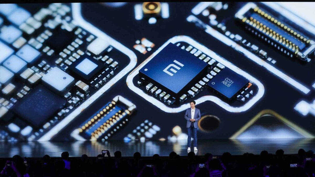 Lei Jun, CEO Xiaomi, menghadirkan chipset eksklusif baru dengan logo 'Mi'. Detail sirkuit menyoroti teknologi mutakhir perusahaan