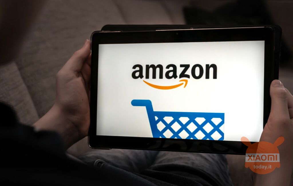 Mani che tengono un amazon fire tablet con il logo dello shopping Amazon su uno schermo nero