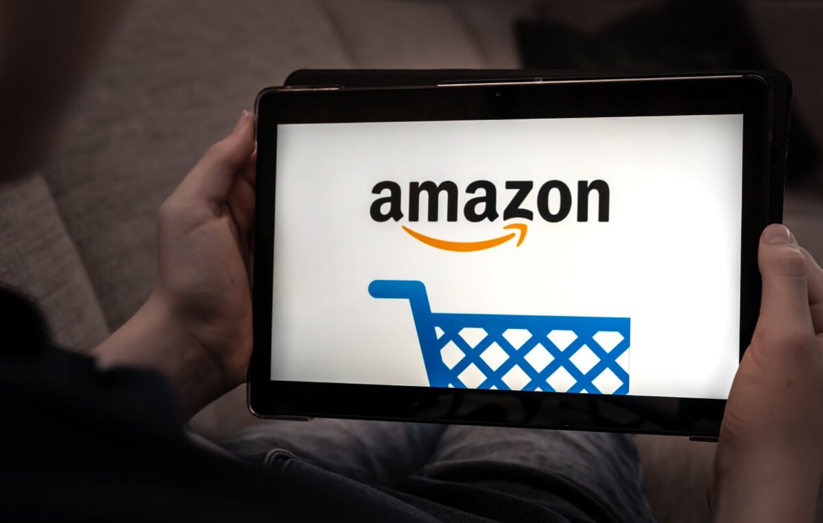 Hande wat 'n Amazon Fire-tablet vashou met die Amazon-winkellogo op 'n swart skerm