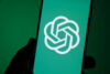 logo di chatgpt su uno smartphone con sfondo verde acqua, il colore dell'azienda. smartphone è tenuto da una mano