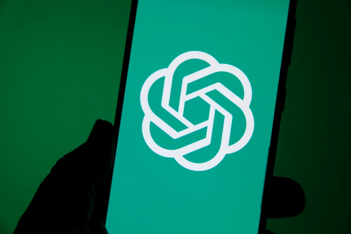 chatgpt-logo op een smartphone met een blauwgroen achtergrond, de bedrijfskleur. smartphone wordt met één hand vastgehouden