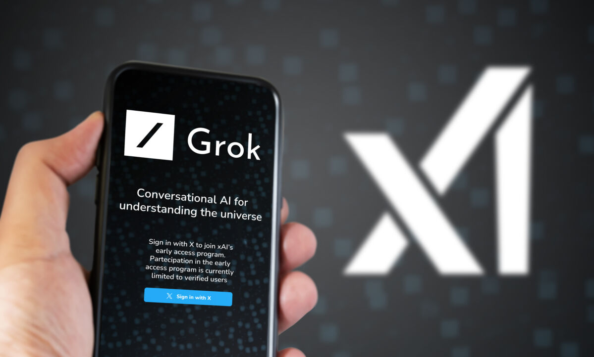 Mâna ținând un smartphone cu pagina de conectare Grok pe ecran