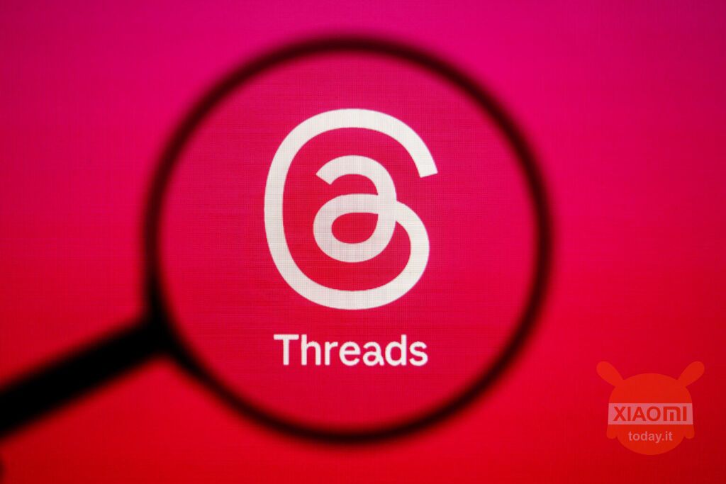 logo di threads su sfondo rosso in evidenza con una lente di ingrandimento