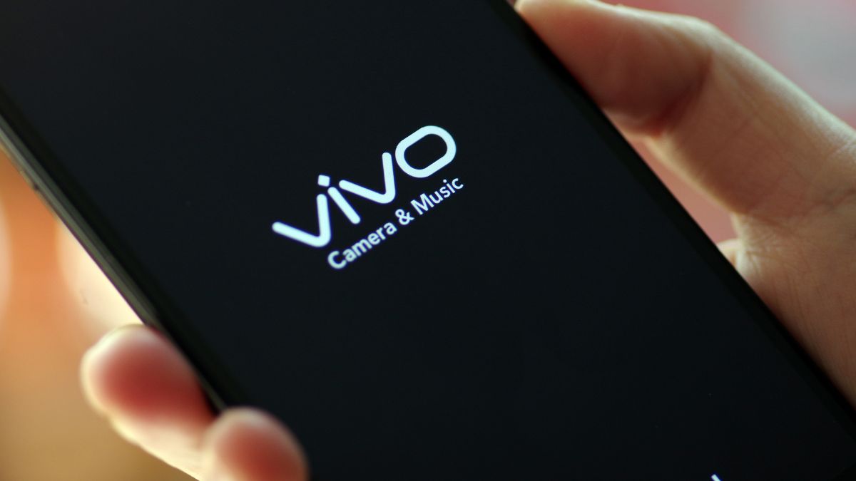 vivo-logo op een smartphone met een zwarte achtergrond en een hand die hem vasthoudt