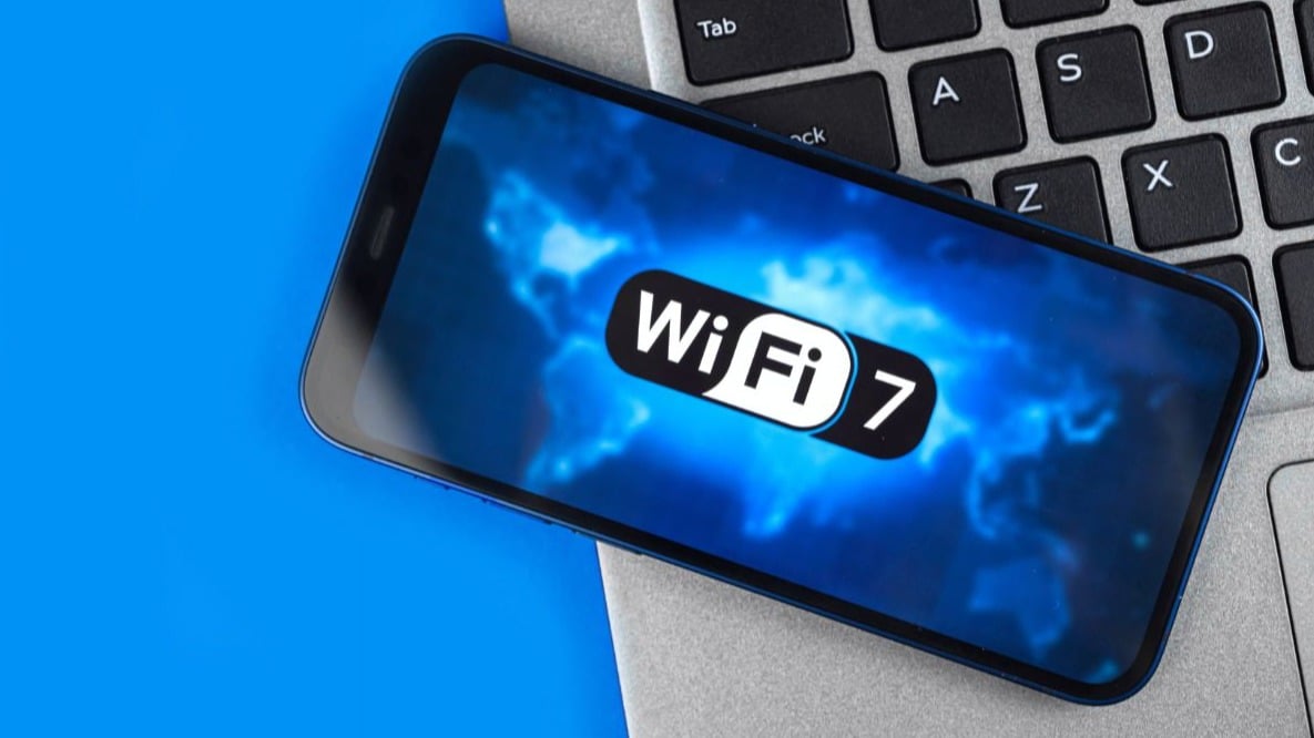 شعار wi-fi 7 على هاتف ذكي بخلفية زرقاء - يتم وضع الهاتف الذكي على جهاز macbook