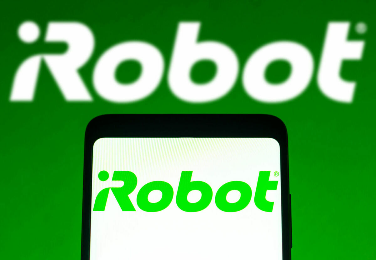 白い背景のスマートフォン上のアイロボットのロゴ。背景には緑の背景に白いアイロボットのロゴ