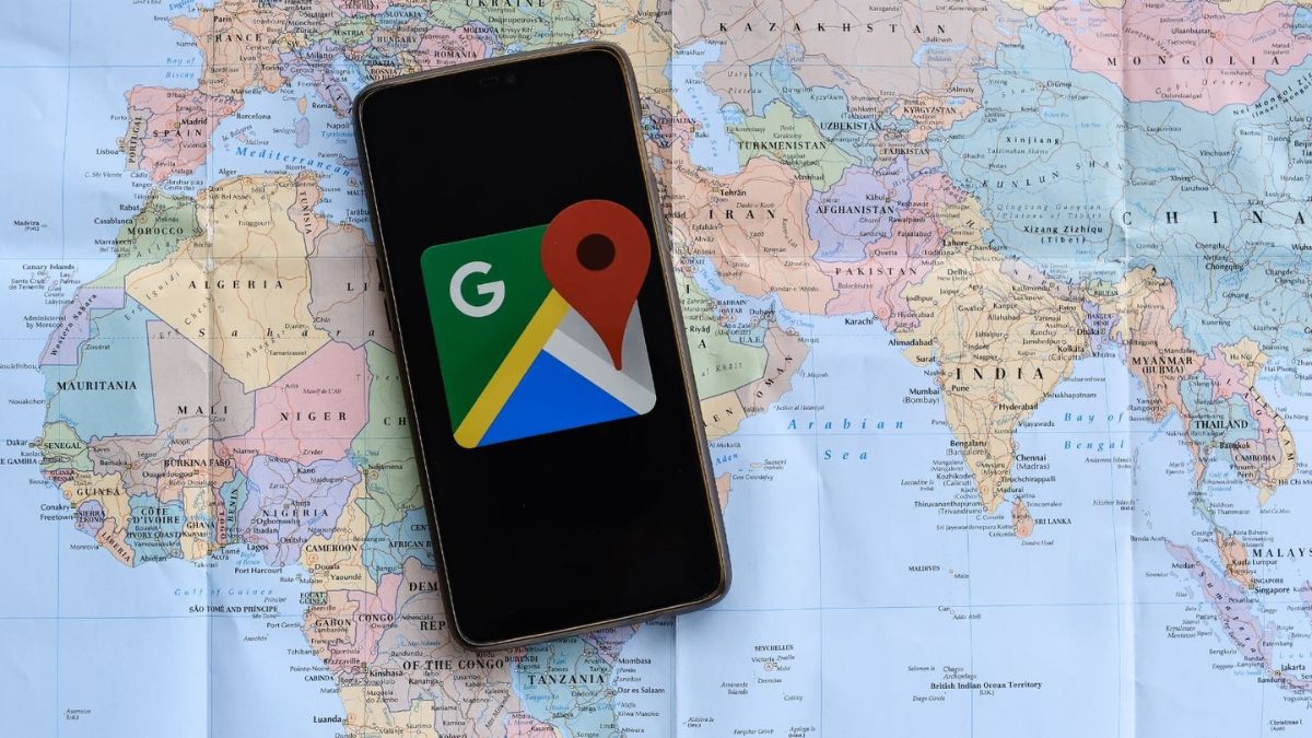 en världskarta med en smartphone på. smarttelefonen har google maps logotyp