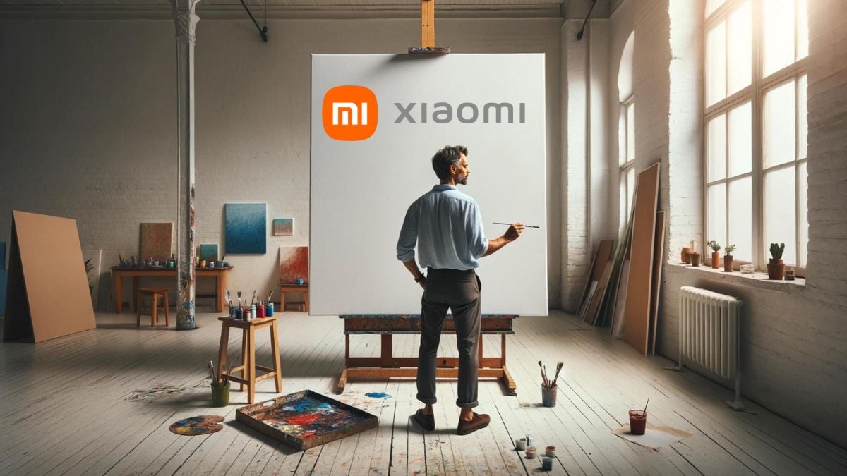 Artist in bright studio paints on a large white canvas with xiaomi logo drawn on it