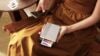 Xiaomi Portable Photo Printer 1S in mano a una donna mentre stampa e viluppa delle fotografie
